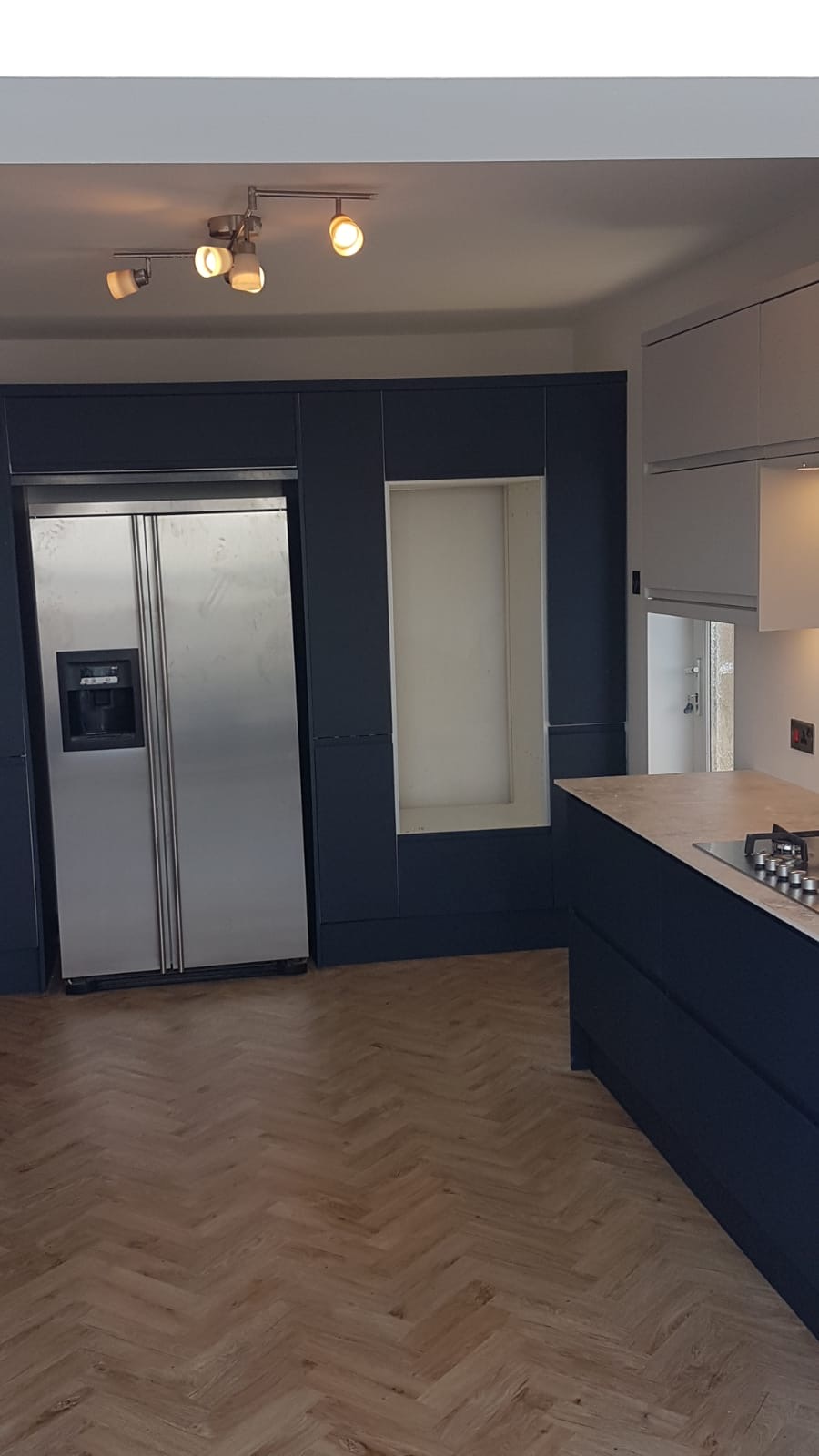 A newly installed navy kitchen with integrated fridge freezer